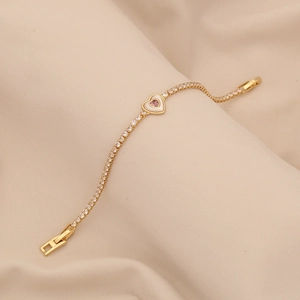 Elegante bracciale a cuore dorato con zirconi rosa su un tessuto di seta beige lussuoso