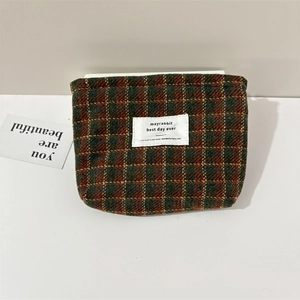Detailed macro view of the wool plaid cosmetic organizer bag with green and brown patterns