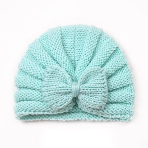 Close-up of mint green knitted baby hat featuring a large soft decorative bow detail