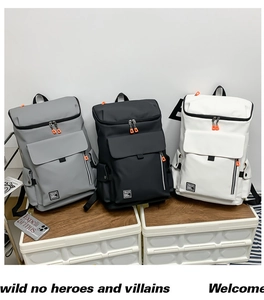 Detail of gray, black, and white waterproof backpacks with orange zipper accents