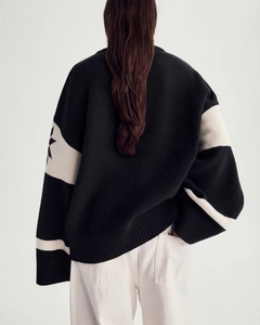 Rear view of loose black knit sweater with white star pattern and ribbed texture detail
