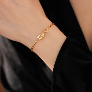 Macro detail of 18K gold-plated bamboo bracelet with cubic zirconia and round charms