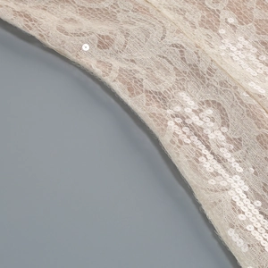Détail de tissu en dentelle crème avec broderie florale et paillettes scintillantes
