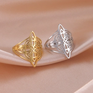 Detailed close-up of gold and silver stainless steel Celtic knot rings on silk fabric