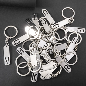 Polished metal keychains with hollowed-out uppercase letters in a stacked macro layout