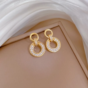 Detailed close-up of golden interlocking hoop earrings with shimmering white pavé zircon