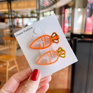 Close-up of cute carrot hair clips in orange and green on a white display card