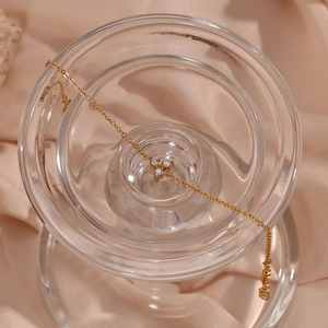 Gold stainless steel lotus bracelet with three white zircon stones on silk background
