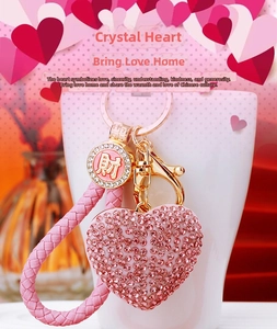 Detailed close-up of pink rhinestone heart keychain with woven strap and gold hardware