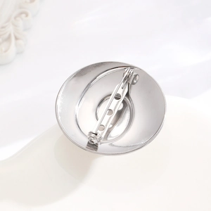 Macro shot of silver polished metal brooch base with secure safety pin back and three holes
