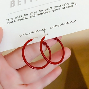 Detailed macro view of minimalist large red hoop earrings with high-gloss finish
