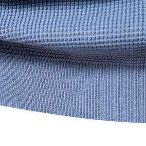 Macro shot of blue waffle knit fabric texture and elastic ribbed hem on the sweater
