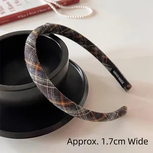 Detail showing 1.7cm wide retro plaid headband with a handmade label on a black plate