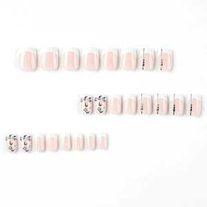 Short French press-on nails with white tips, black flower designs and pink base