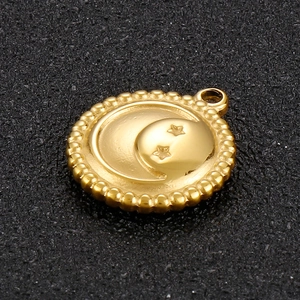 Macro shot of gold stainless steel pendant with moon and stars engraving and beaded edges