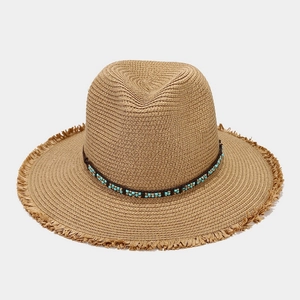 Détail d'un chapeau de paille bohème avec bandeau en cuir perlé et bords effilochés