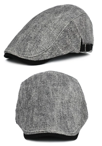 Detail view of grey tweed flat cap showing textured fabric and black corduroy brim lining