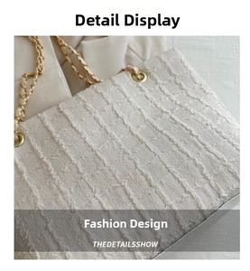 Detail of off-white tote bag featuring textured woven fabric and gold chain shoulder strap