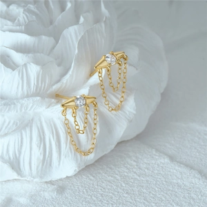 Macro shot of gold tassel earrings with clear zircon stones and geometric studs