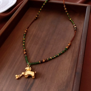 Detail of beaded necklace with tiger eye glass and golden auspicious beast pendant