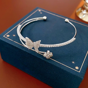 Detail of silver double-layer open bangle with zircon butterfly and clover on jewelry box