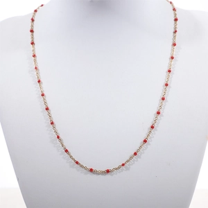 Detail of a gold stainless steel beaded necklace with vibrant red enamel beads for women
