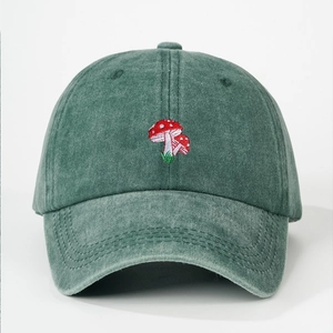 Detailed view of mushroom embroidery on retro washed green cotton baseball cap