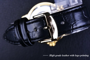 Macro shot of black crocodile-embossed leather strap with a golden branded buckle