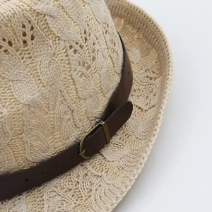 Detailed macro view of beige straw hat weaving with brown faux leather belt and metal buckle