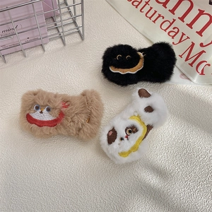 Close-up of cute plush animal brooches in black, brown, and white with embroidery