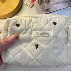 Makroaufnahme der cremefarbenen Stepptasche mit brauner Herzstickerei und Reißverschluss