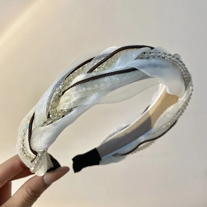 Detailed shot of white organza woven headband with crystal beads and twisted design
