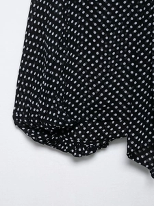 Detail shot of black and white polka dot chiffon fabric with elegant draping and pleats