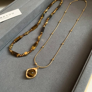 Detail of layered gold-plated necklaces with tiger eye beads in a velvet jewelry box