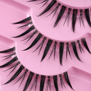 Faux cils noirs naturels épais style manga pointu sur un plateau rose