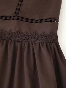 Dettaglio di un abito marrone scuro con scollo a V, ricamo in pizzo e design traforato