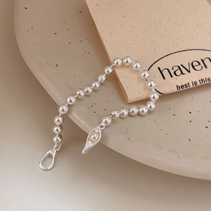 Minimalist 925 sterling silver beaded bracelet with a pearl pea pod pendant on ceramic tray