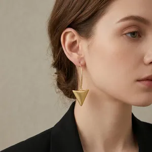 Minimalist 18k brushed gold triangle drop earrings with matte finish on model