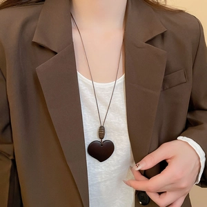 Close-up of vintage dark brown resin heart pendant necklace worn on a female model