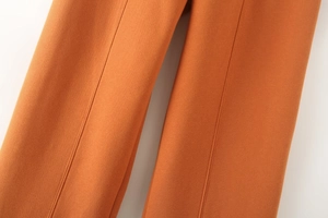 Close-up of orange sweatpants featuring center-seam pleats and soft velvet texture