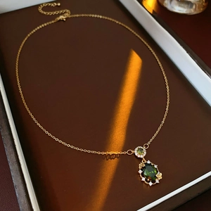 Macro shot of gold butterfly necklace with green emerald stone and zircon inlay