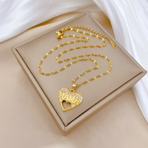 Macro detail of gold-plated heart necklace with MAMA lettering and crystal paving