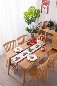 Detail view of a plaid Christmas table runner with truck and tree on a festive table