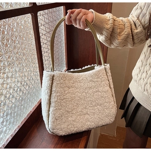 Close-up of beige fleece tote bag with olive green handles held against a wooden window