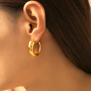 Polished 18k gold plated C-shaped geometric hoop earrings worn by a female model