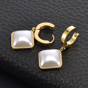 Créoles dorées avec pendentifs en perles blanches carrées sur cuir noir texturé