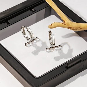 Gros plan de boucles d'oreilles argentées avec perles et diamants en écrin noir