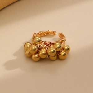 Close-up of golden open ring with irregular textured band and polished metal bead cluster