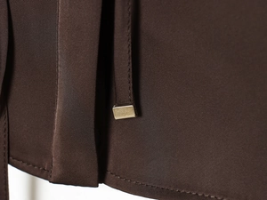 Detailed macro view of dark brown poplin fabric with metallic buckle and strap closure