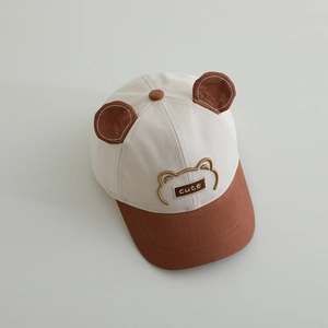 Détail des oreilles d'ours et de l'écusson brodé sur la casquette bicolore pour enfant
